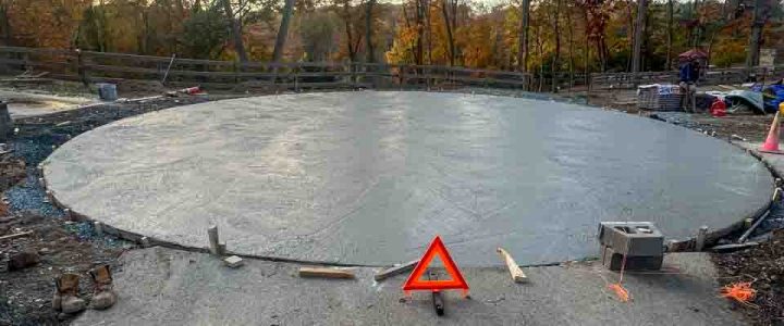 A smooth, finished concrete slab with construction tools and safety markers visible, indicating recent work.
