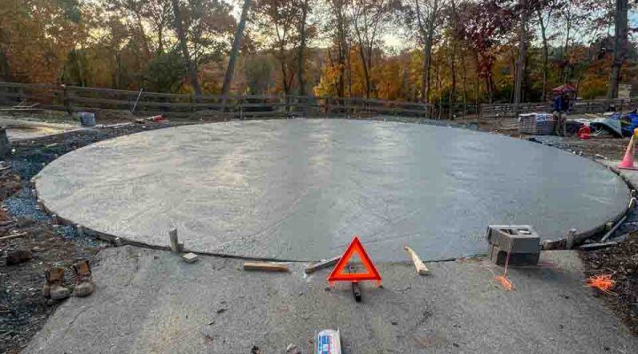 A smooth, finished concrete slab with construction tools and safety markers visible, indicating recent work.