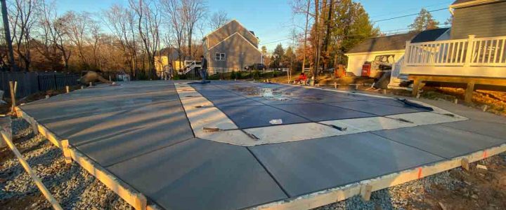 A newly poured concrete slab being smoothed out in an outdoor setting.