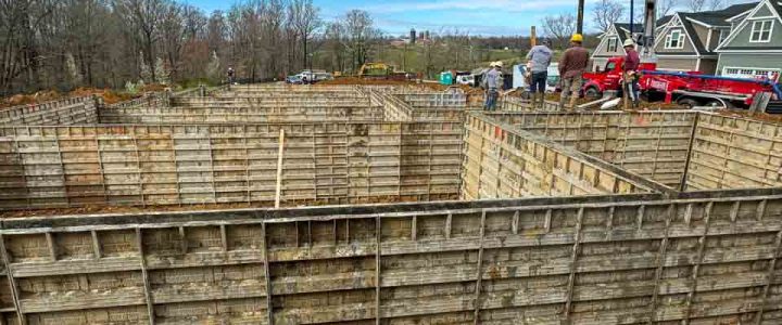 Wooden forms set up for pouring concrete, part of the foundation construction process at a building site.