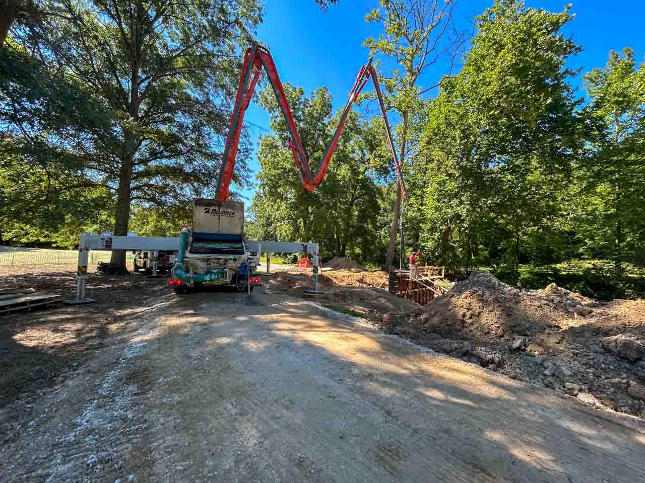 A concrete pump truck positioned at a residential construction site, preparing to pour concrete into forms.